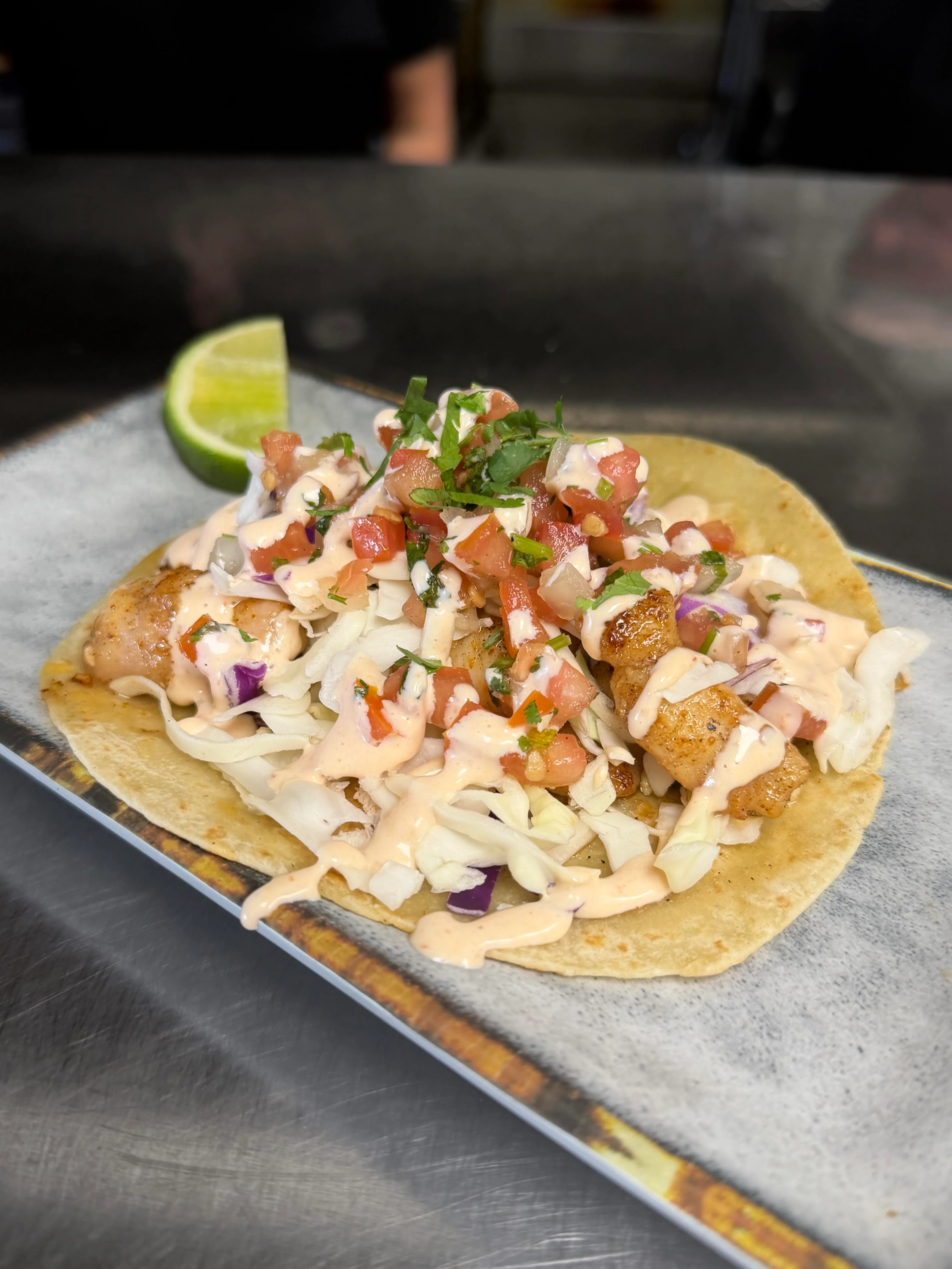 A vibrant dish of shrimp and diced vegetables, garnished with avocado slices and fresh cilantro, served on a dark plate.
