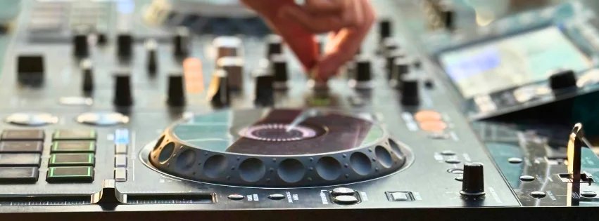 Close-up of a DJ mixer with a hand adjusting the controls.