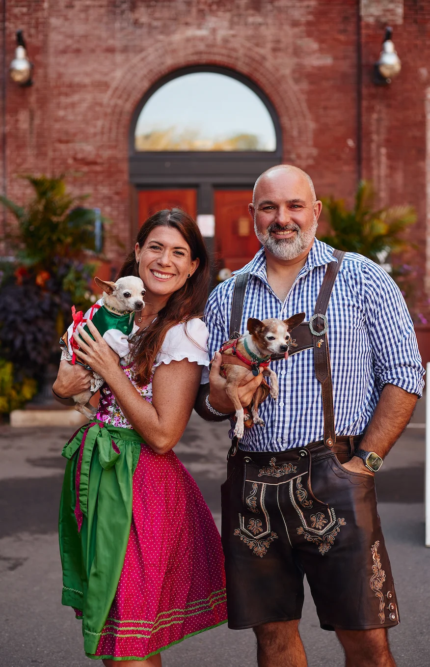 Couple in traditional attire with dogs outside a rustic venue