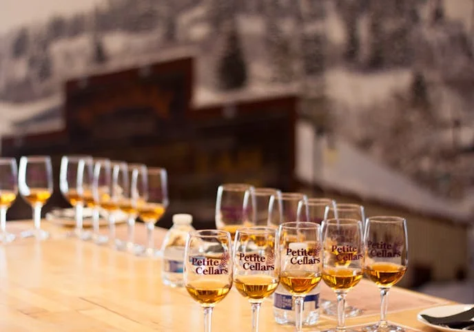 Tasting glasses of whiskey lined up on a wooden bar