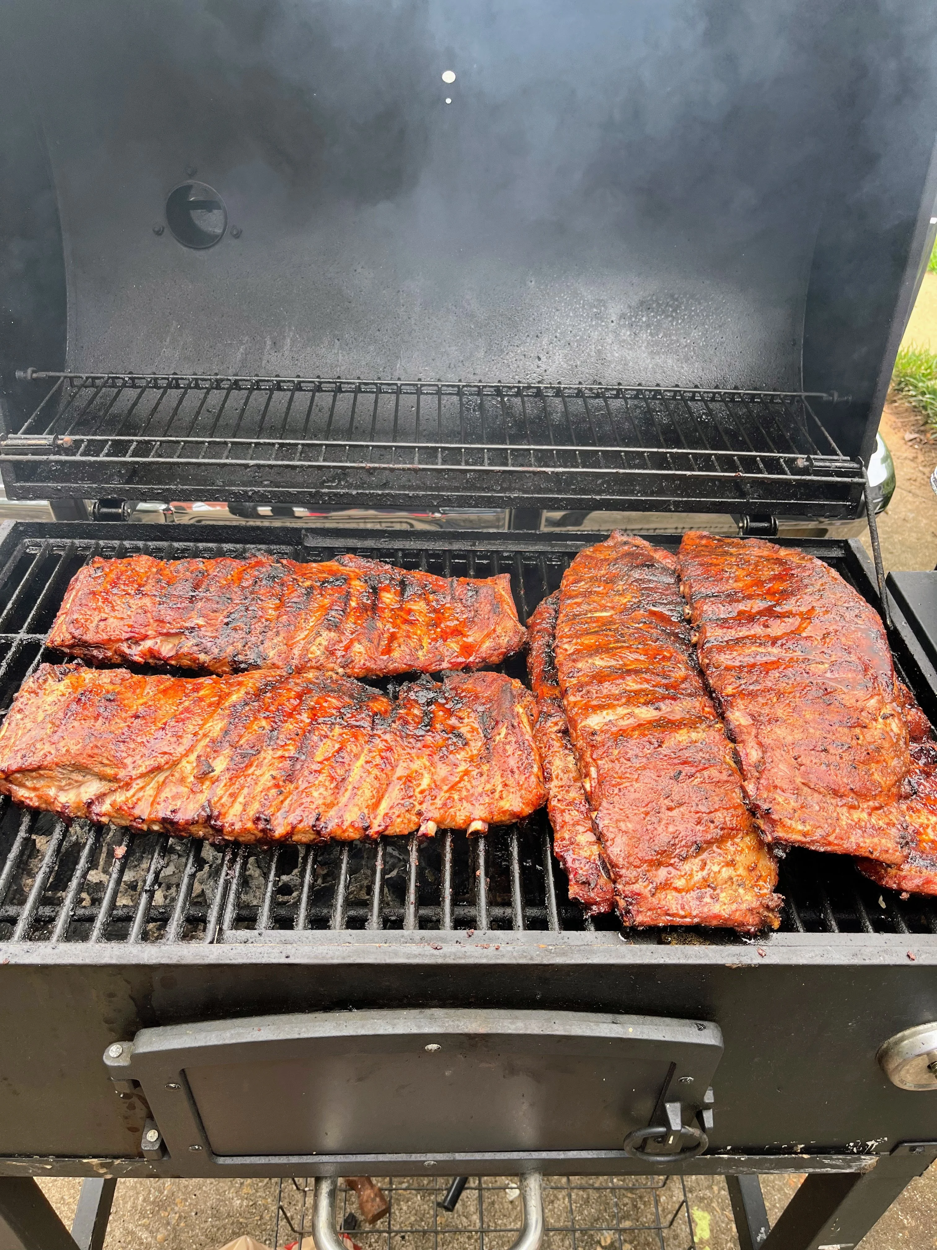 A grill filled with succulent ribs, showing a rich glaze and smoke rising in the background.