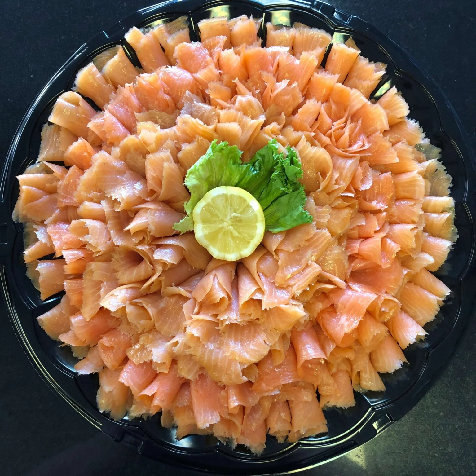 Platter of smoked salmon garnished with lemon and lettuce