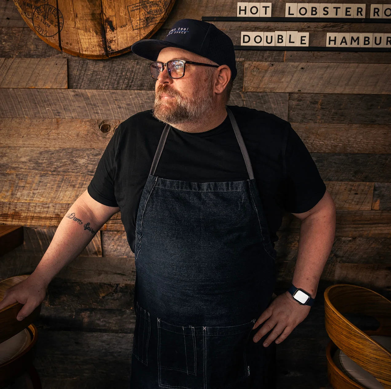 Chef in denim apron posing in a rustic restaurant interior