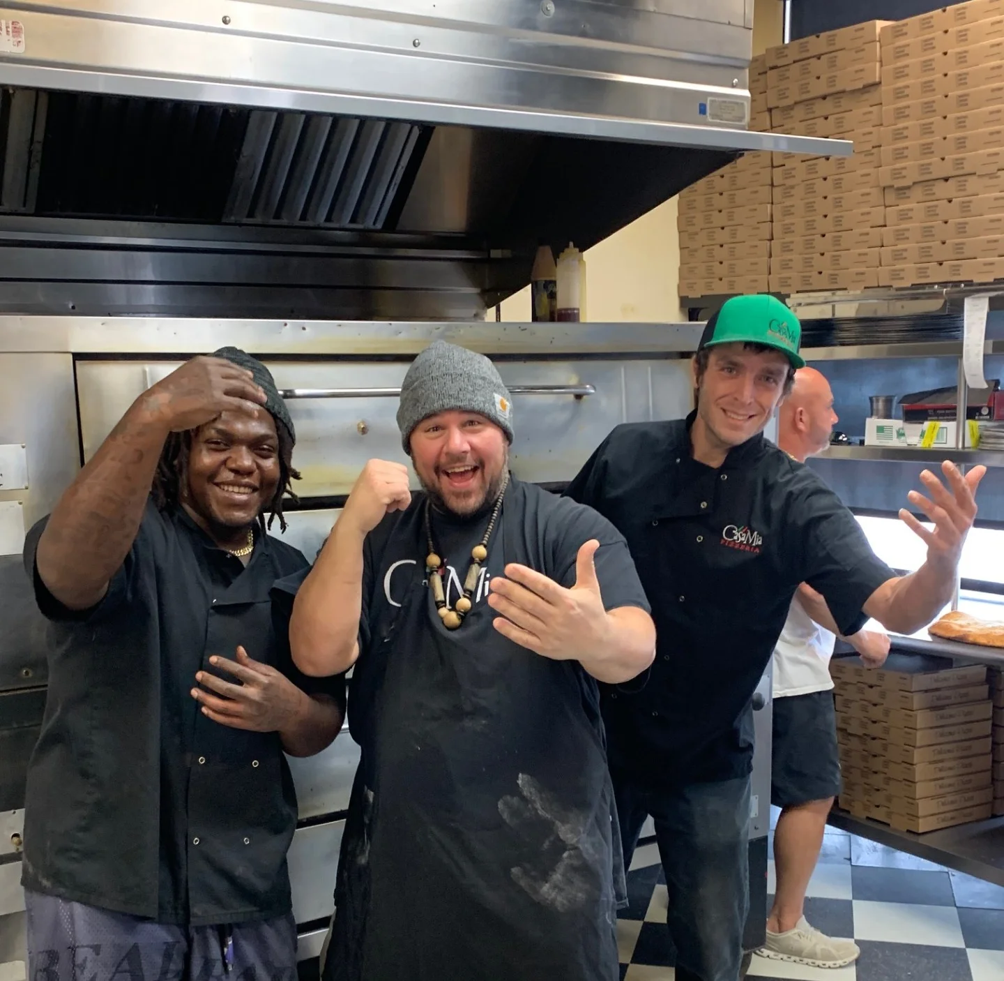 Chefs posing playfully in a bustling restaurant kitchen