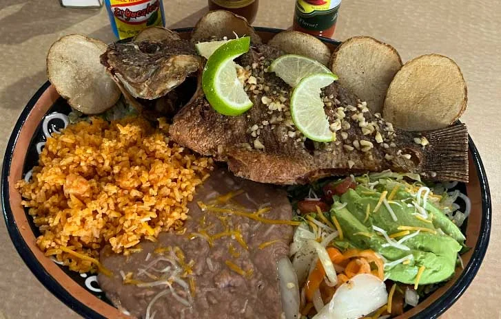Whole fried fish served with rice and beans in a Mexican platter