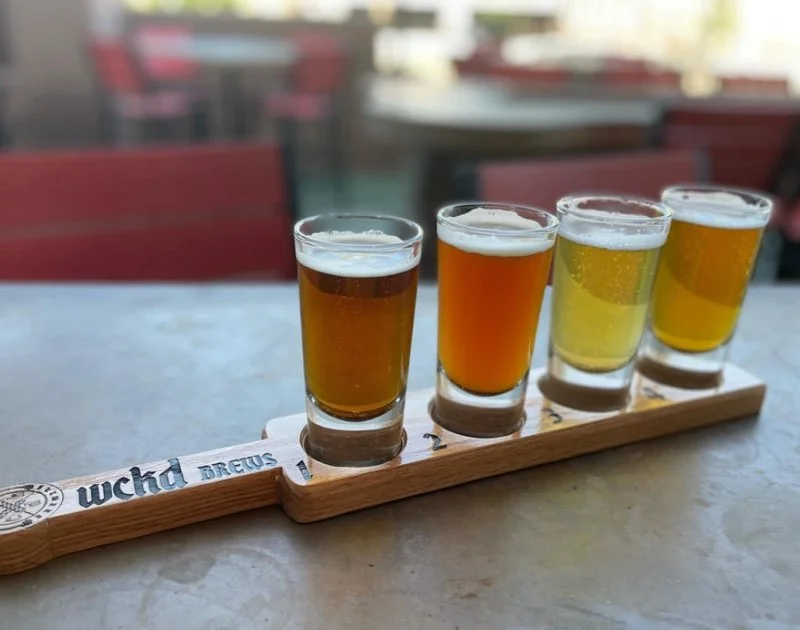 Craft beer flight with four distinct brews on a wooden paddle