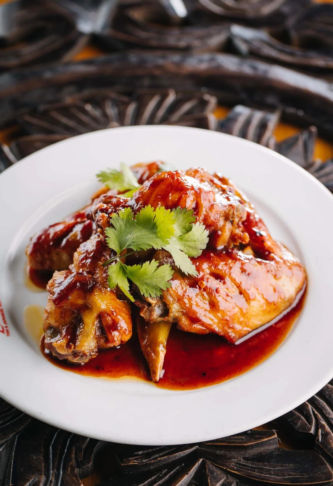 Sticky Asian chicken wings with glaze and cilantro garnish
