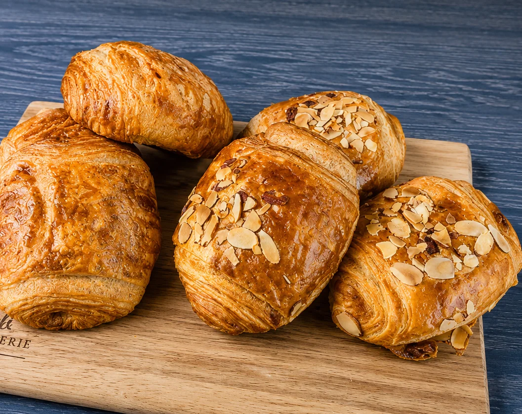 Freshly baked croissants and pastries on a wooden board.