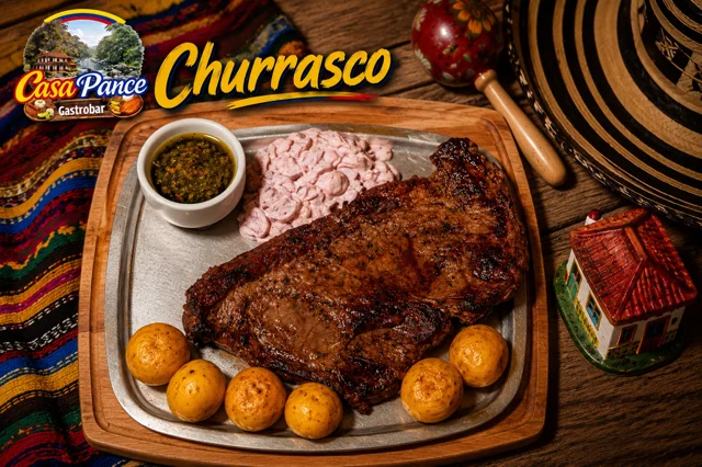 A serving of grilled churrasco beef, accompanied by dipping sauces and small potatoes on a metal platter.