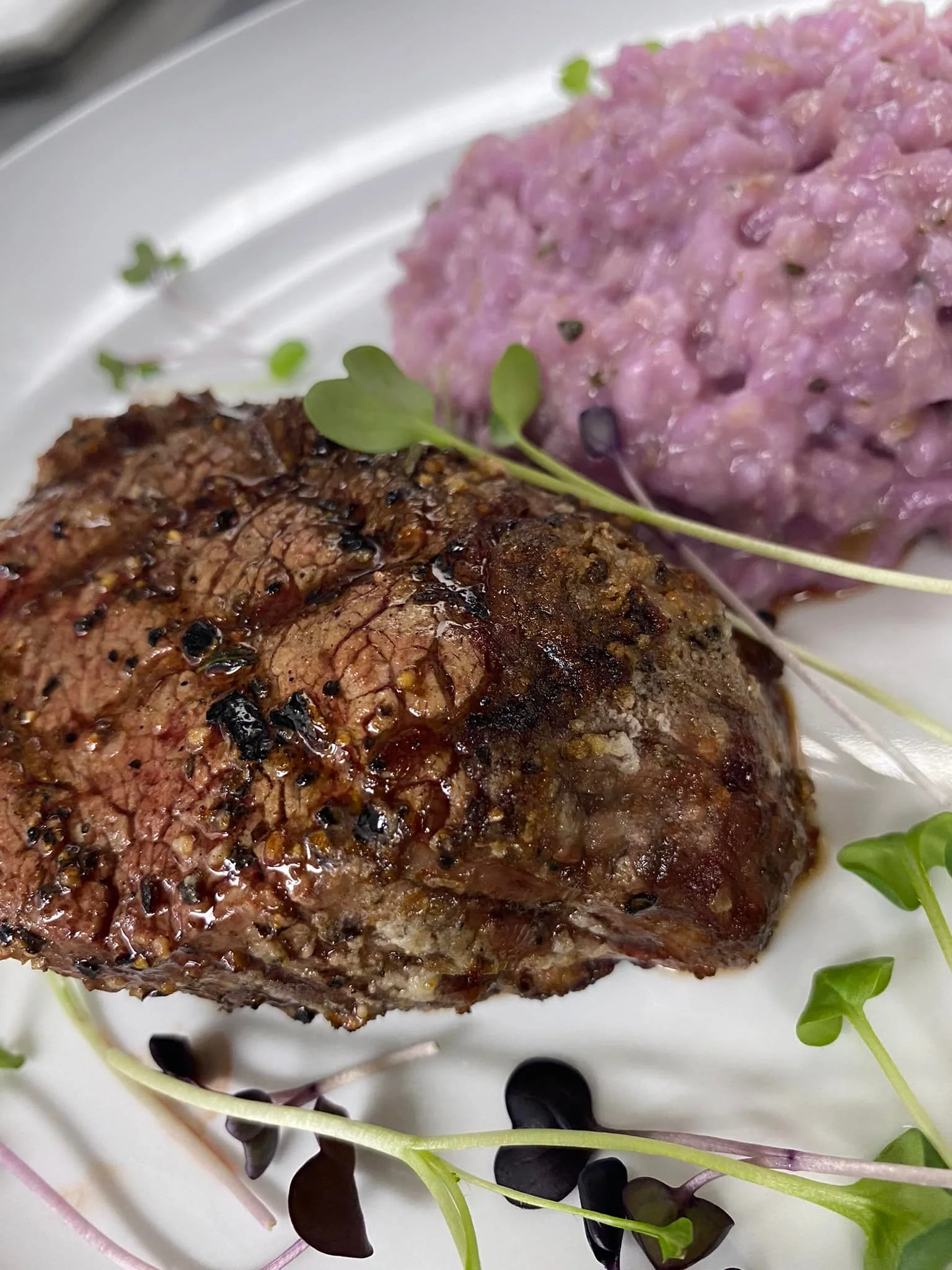 Grilled steak with purple risotto and microgreens