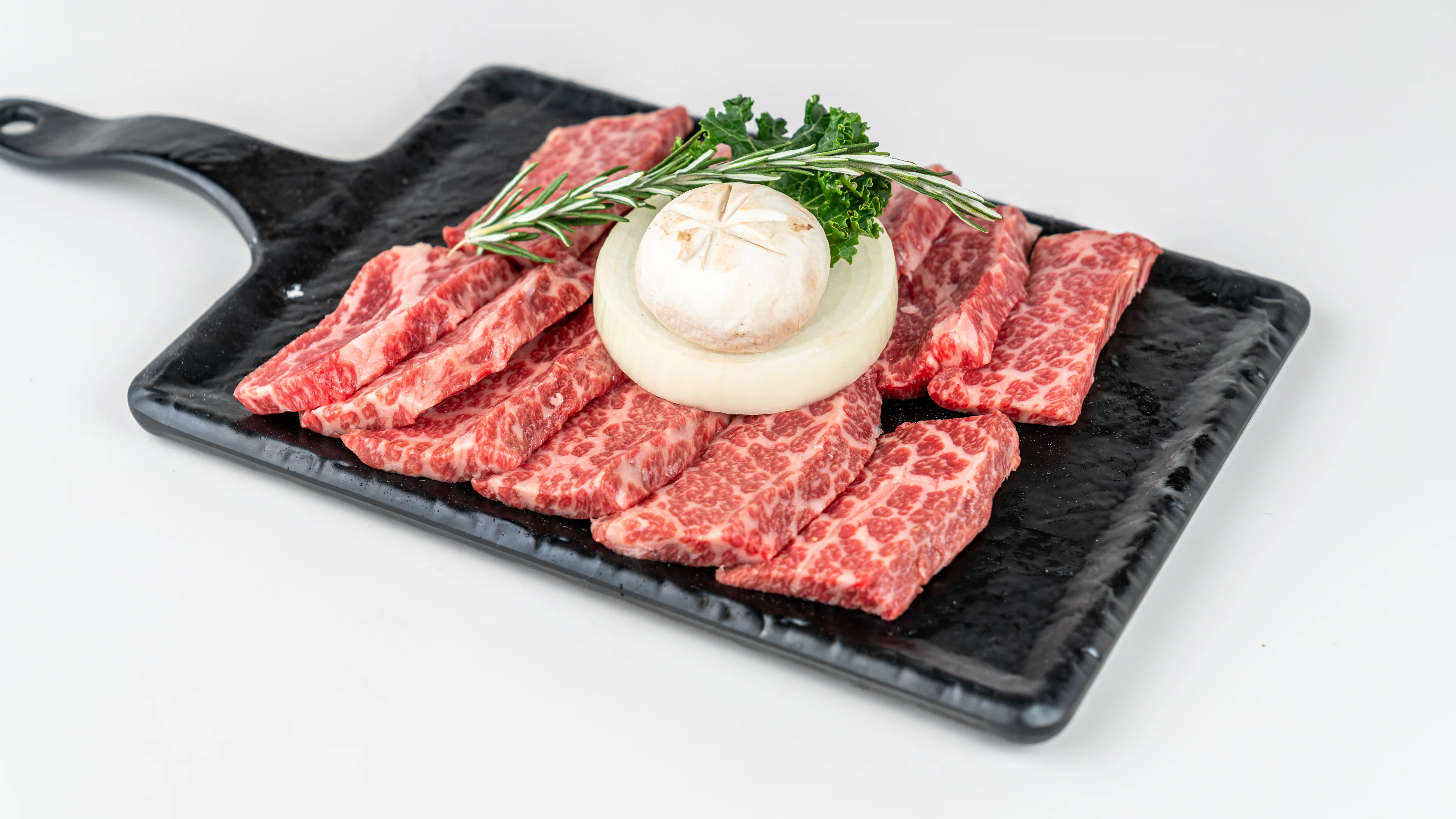 Premium Japanese wagyu beef slices on a black platter