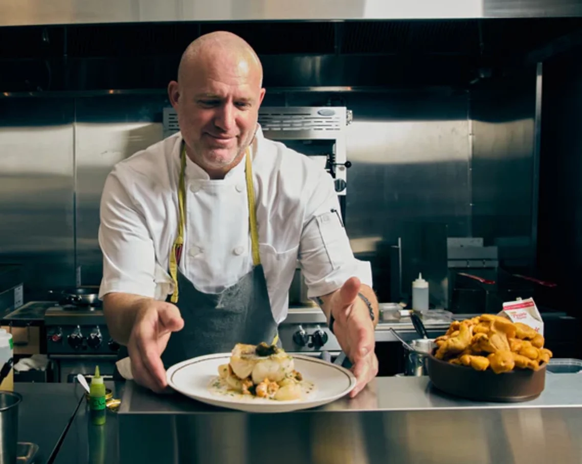 Chef presenting a beautifully plated seafood dish in a modern kitchen
