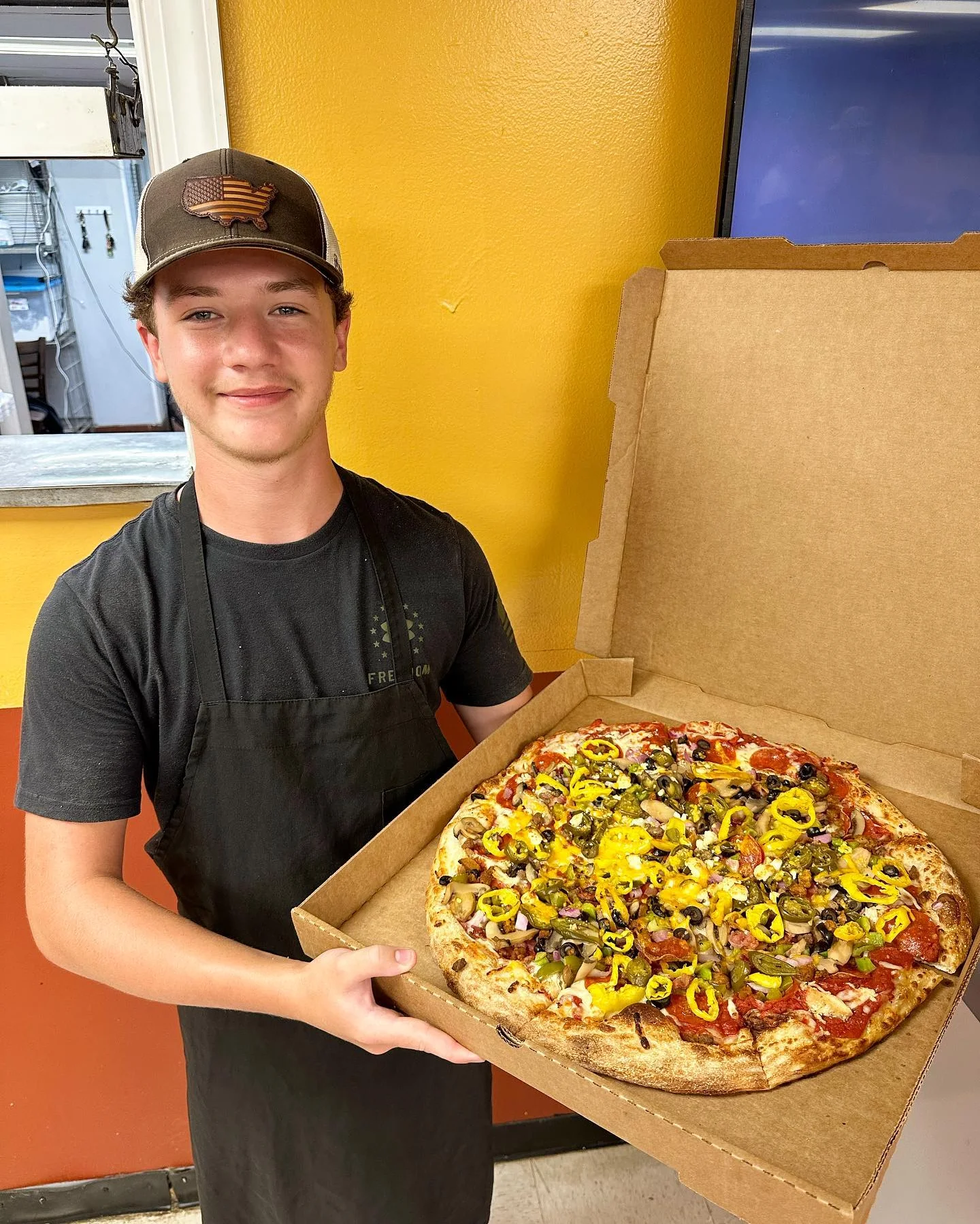 Ranked Best Pizza in Alabama, Boy holding extra large pizza, one of largest pizzas around the belt buster at cutter's pizzeria of alexandria, AL