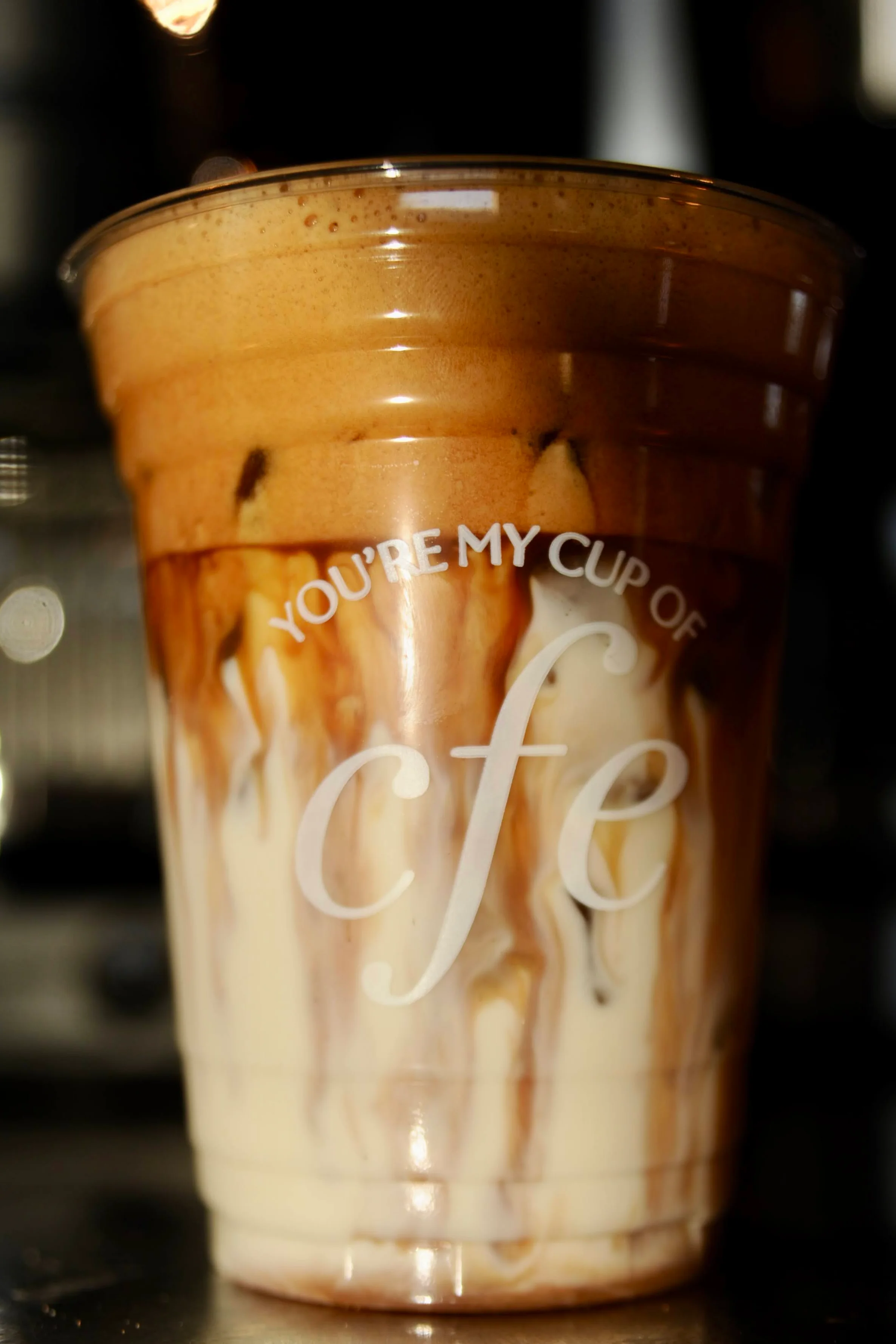 Four colorful iced beverages in clear cups, decorated with flowers and various toppings.