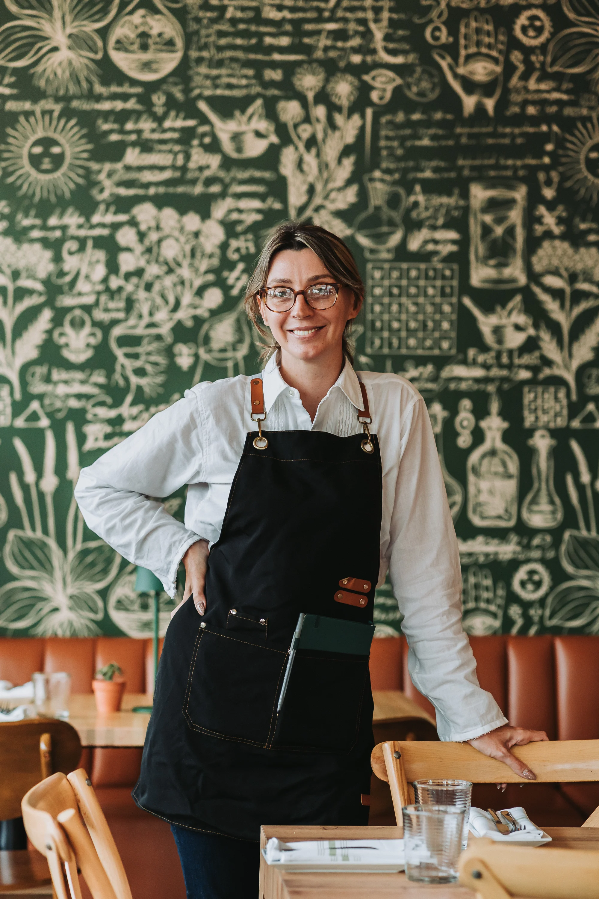 Friendly server in a cozy restaurant with a chalkboard mural
