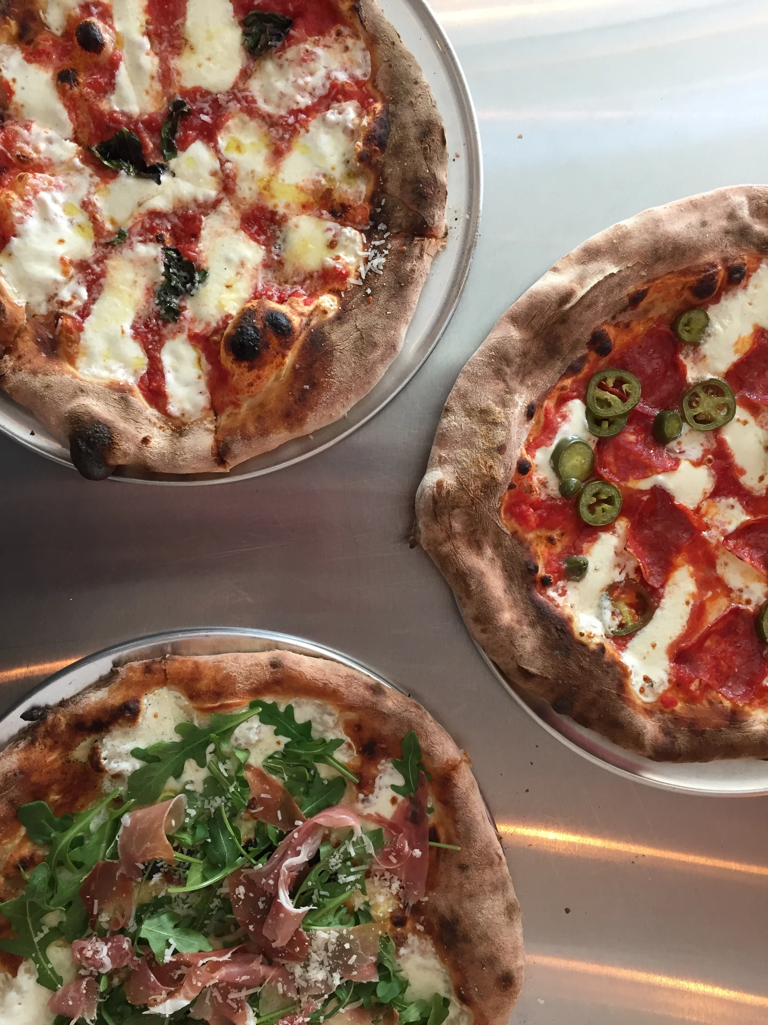 Three artisanal pizzas including Margherita and prosciutto