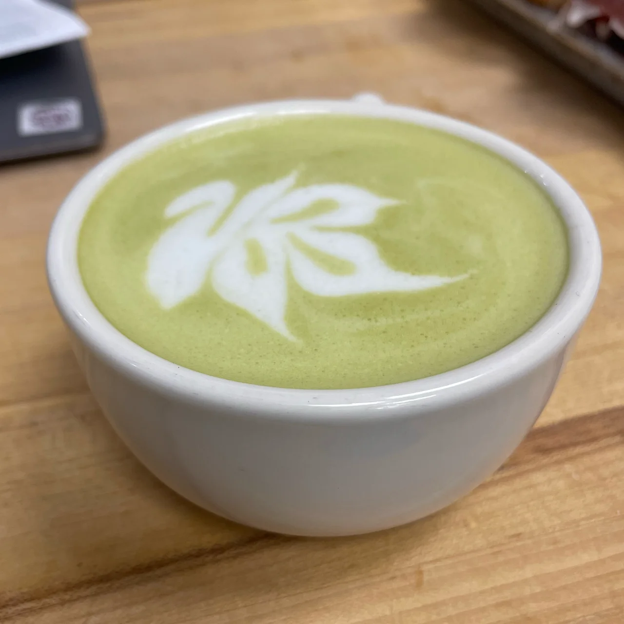 Matcha latte with artistic foam design in a white bowl