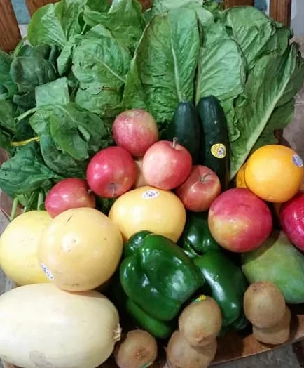 Fresh assortment of colorful vegetables and fruits on a wooden chair