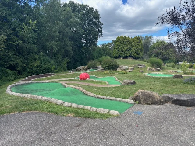 Mini golf course with vibrant green turf and a large red ball
