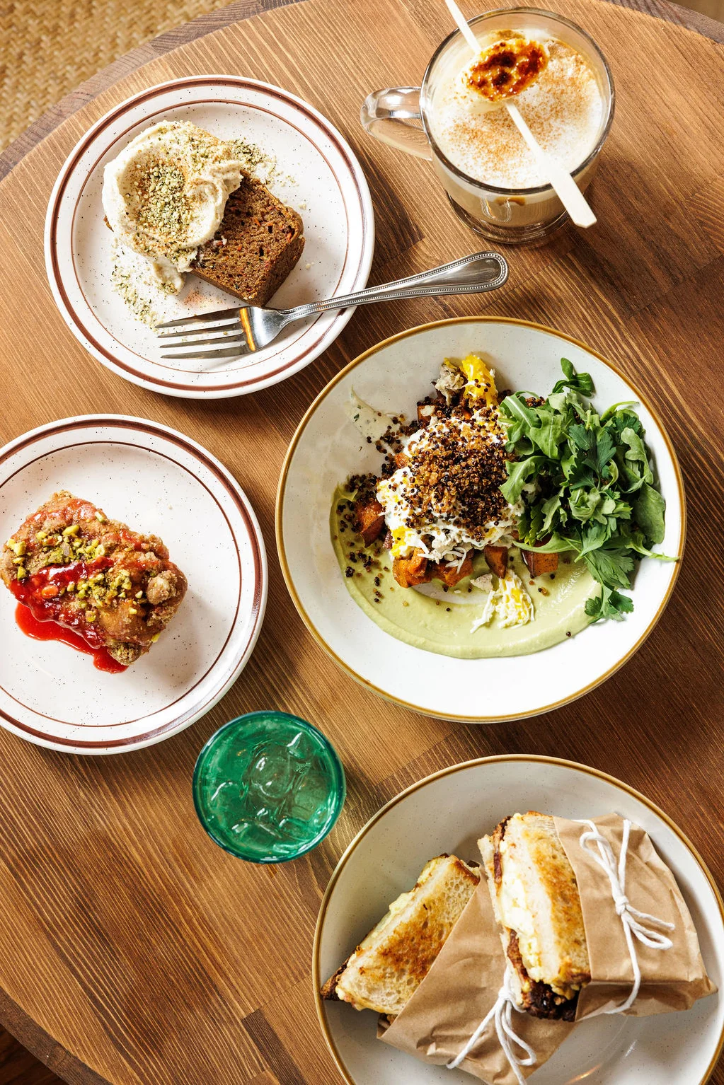 A stylized tablescape of the zucchini carrot cake & various breakfast pastries and sandwiches with bacon.
