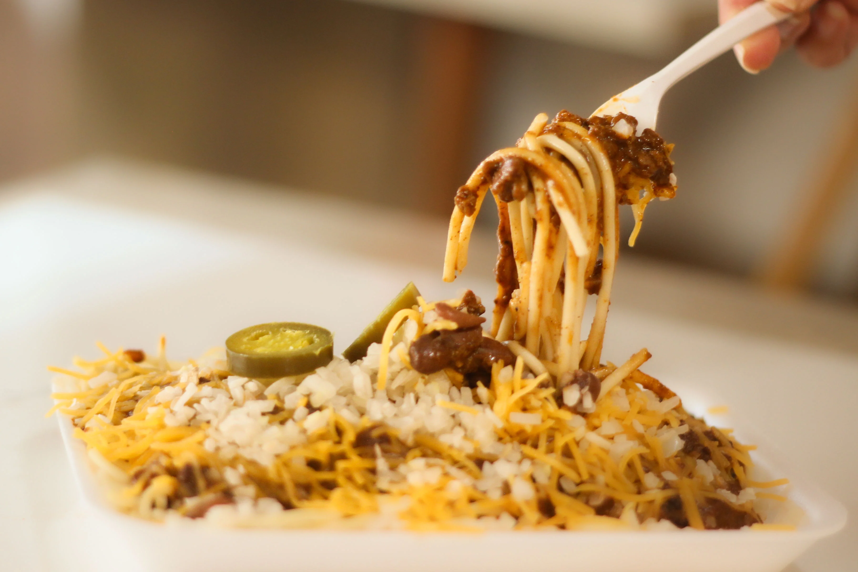 A hearty serving of spaghetti topped with meat sauce, shredded cheese, and garnished with jalapeño slices on a white dish.