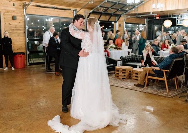Couple dancing at a wedding reception in a rustic venue.