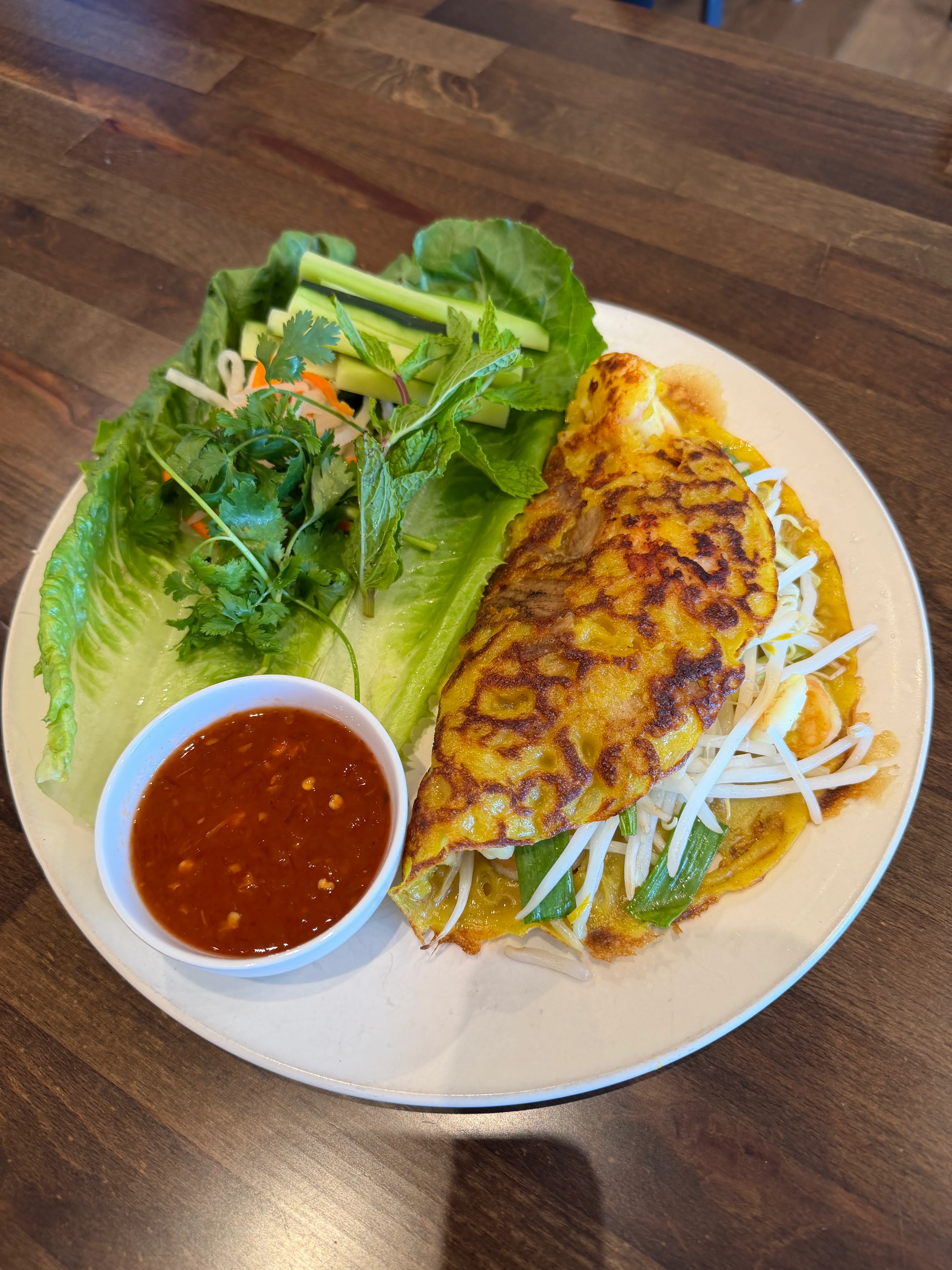 Vietnamese banh xeo with fresh herbs and dipping sauce