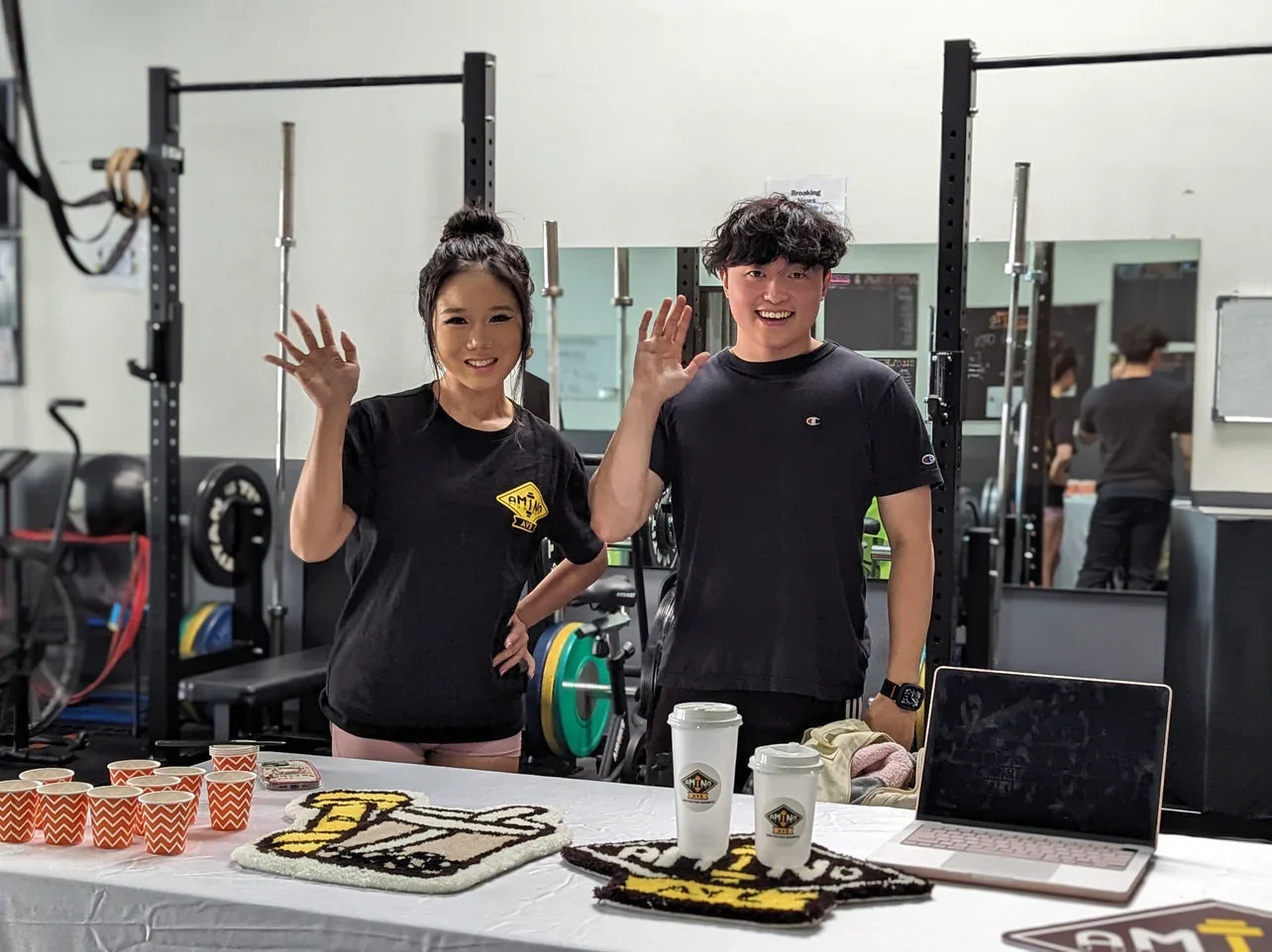 Two smiling individuals at a fitness event with refreshments