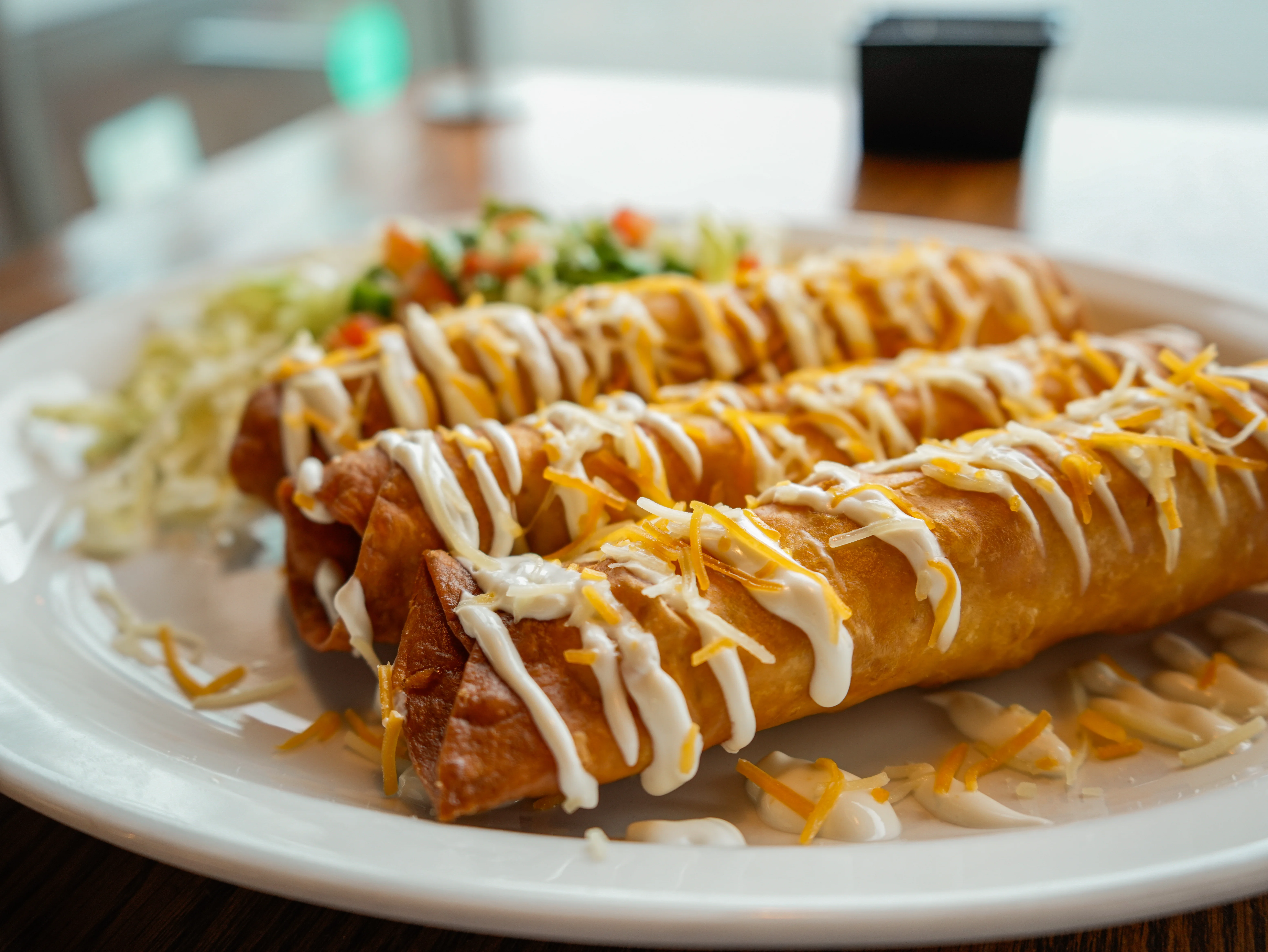 Crispy Mexican flautas drizzled with sour cream and cheese