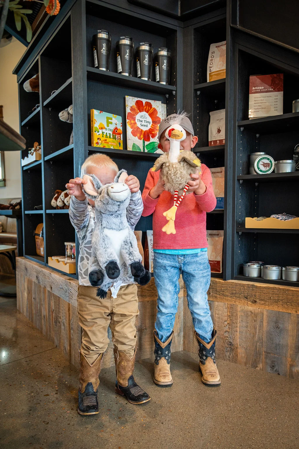 Children holding plush toys in a cozy cafe setting