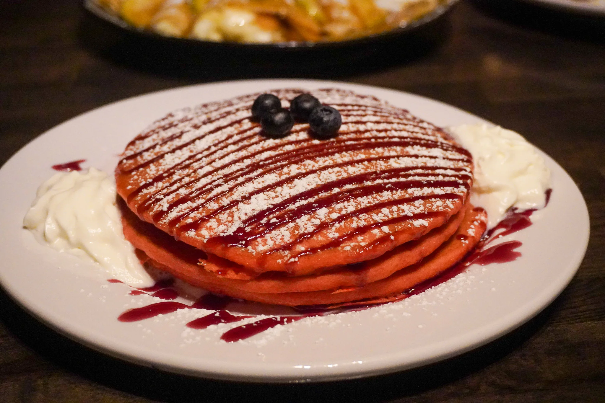 Fluffy red velvet pancakes with blueberries and whipped cream