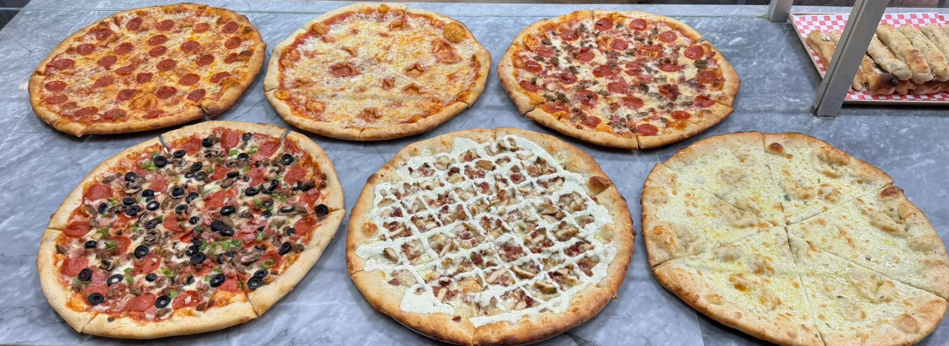 Variety of pizzas including pepperoni and white pizza