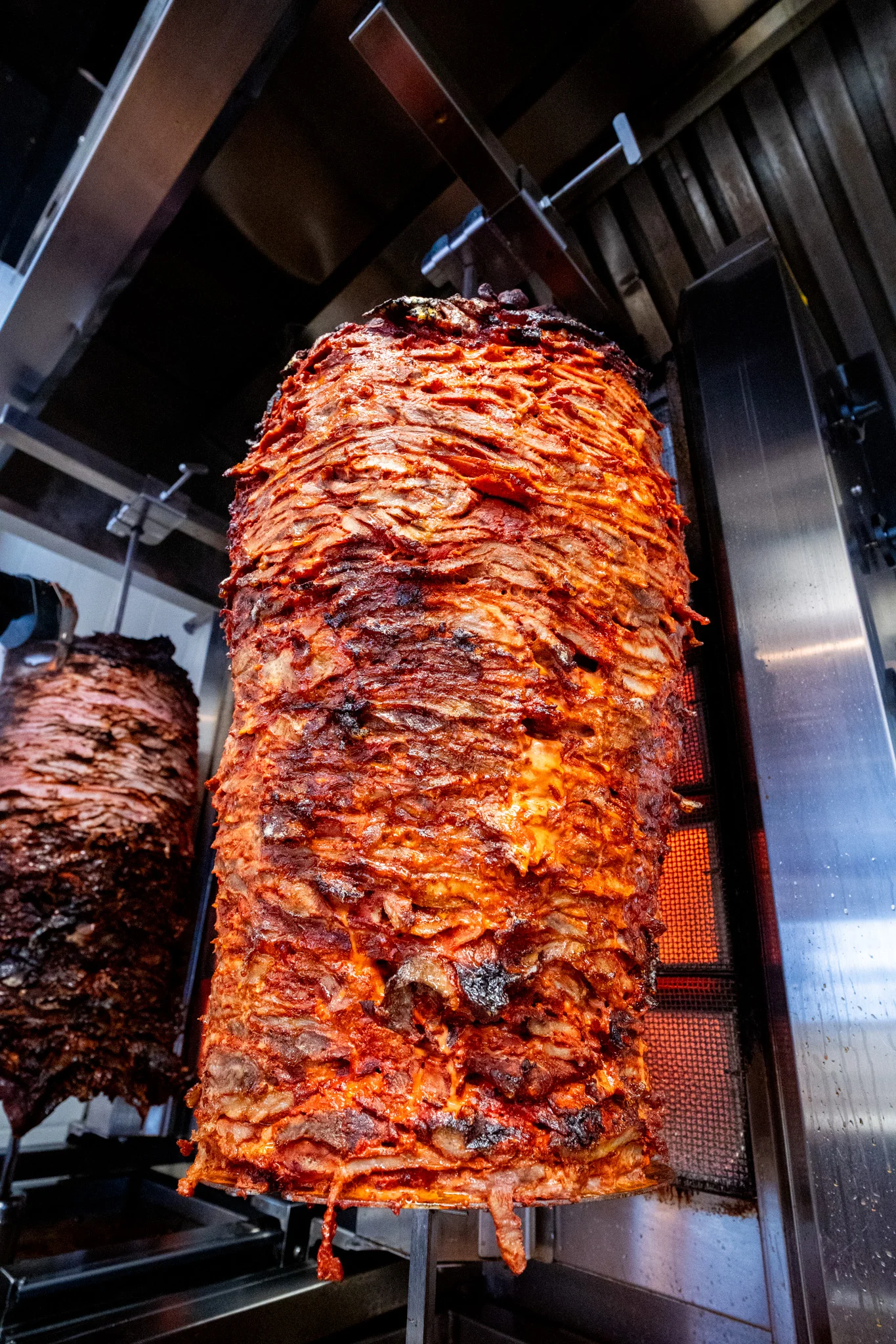Vertical stack of marinated meat on a vertical rotisserie grill.