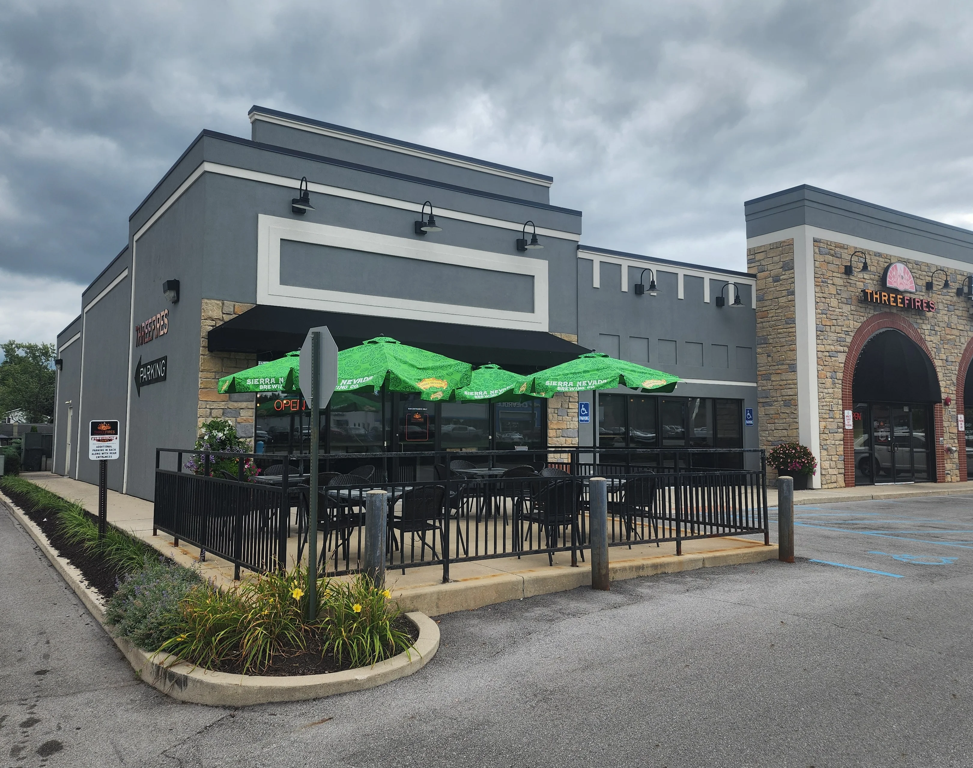 Modern restaurant exterior with outdoor seating and green umbrellas
