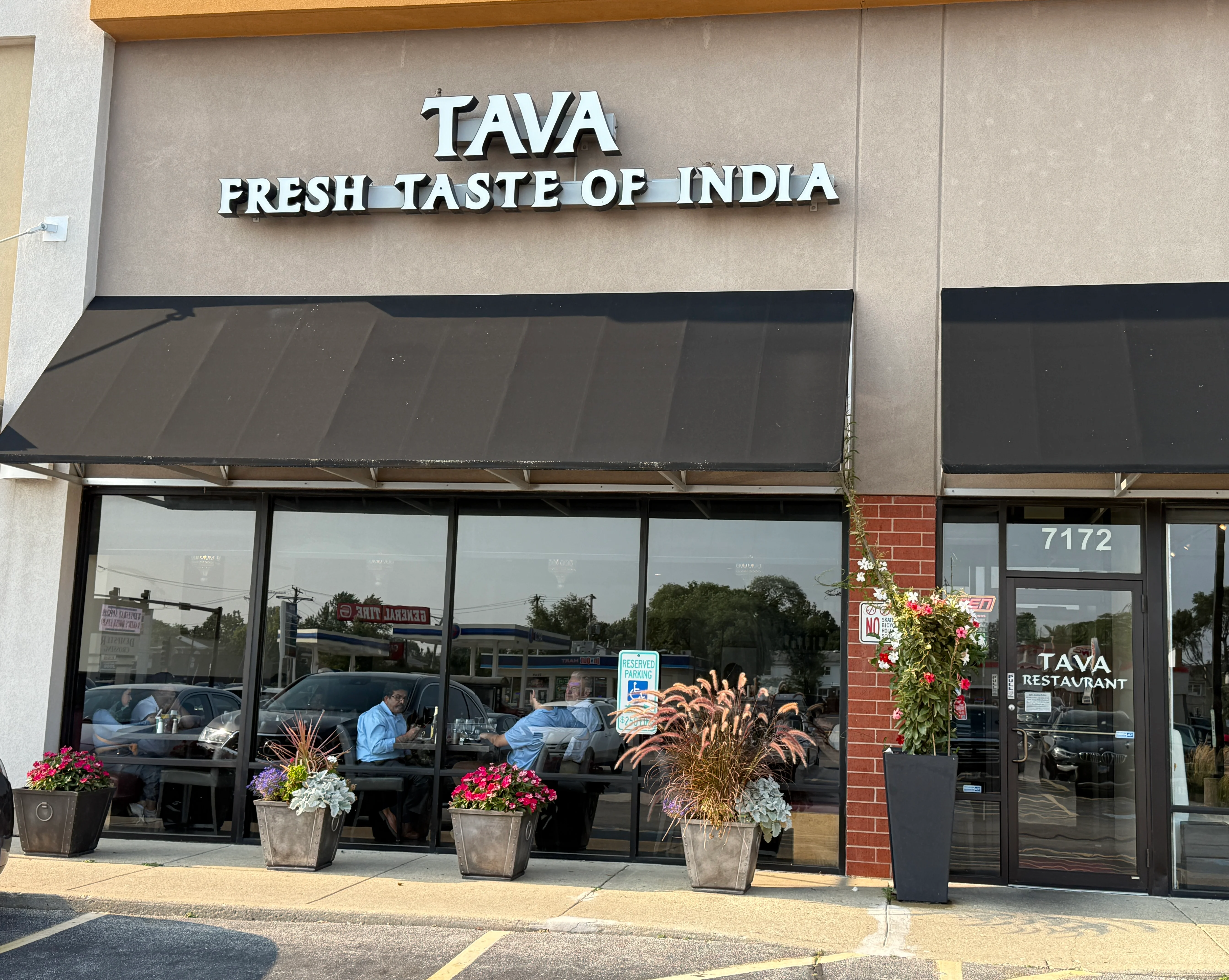 Exterior view of Tava Indian restaurant with vibrant flowers