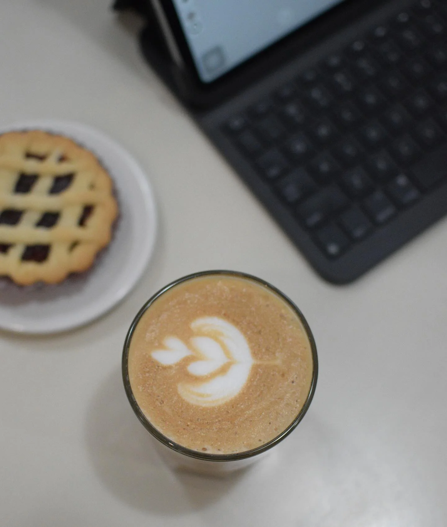 Latte art in a glass with a pastry on the side