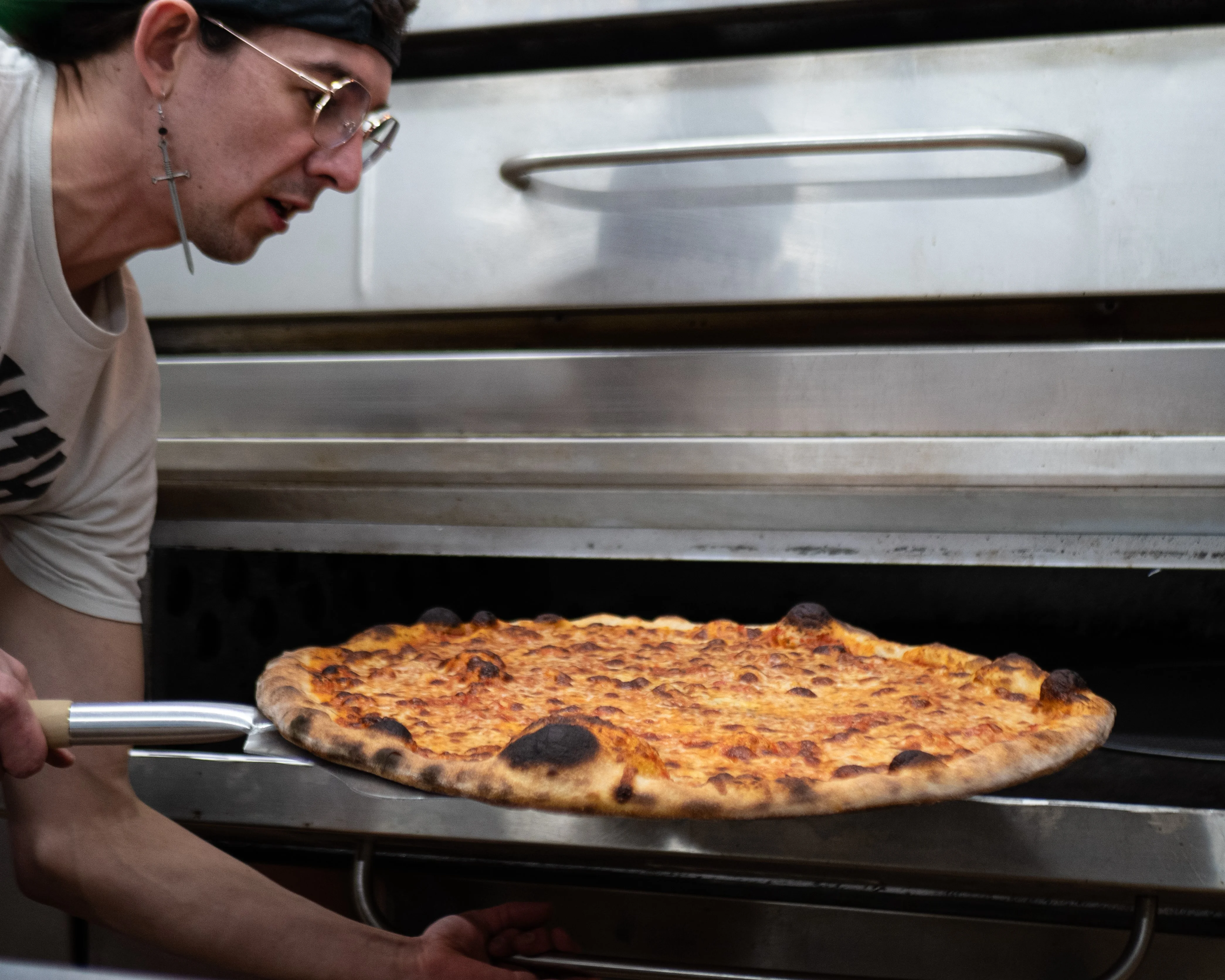 Wes pulling the very first pizza pie out of the oven