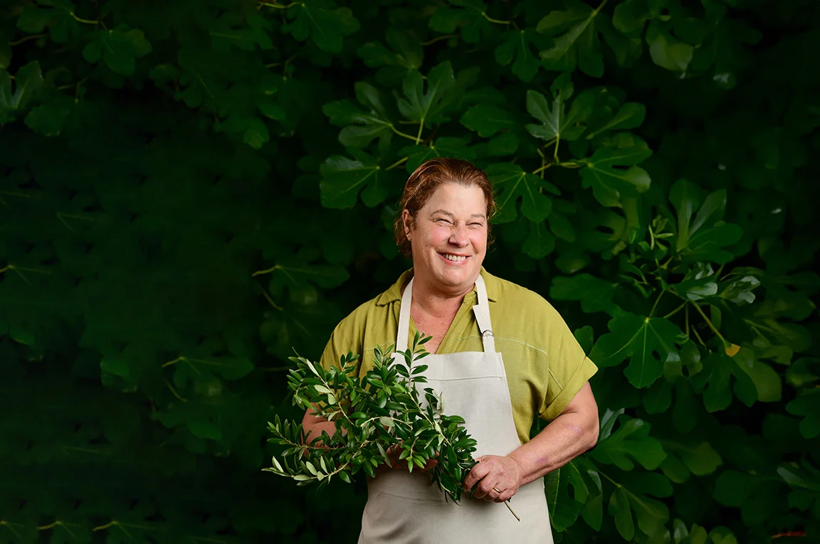 Chef holding fresh herbs in a lush green garden
