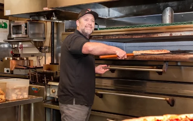 Chef placing pizza in a commercial oven