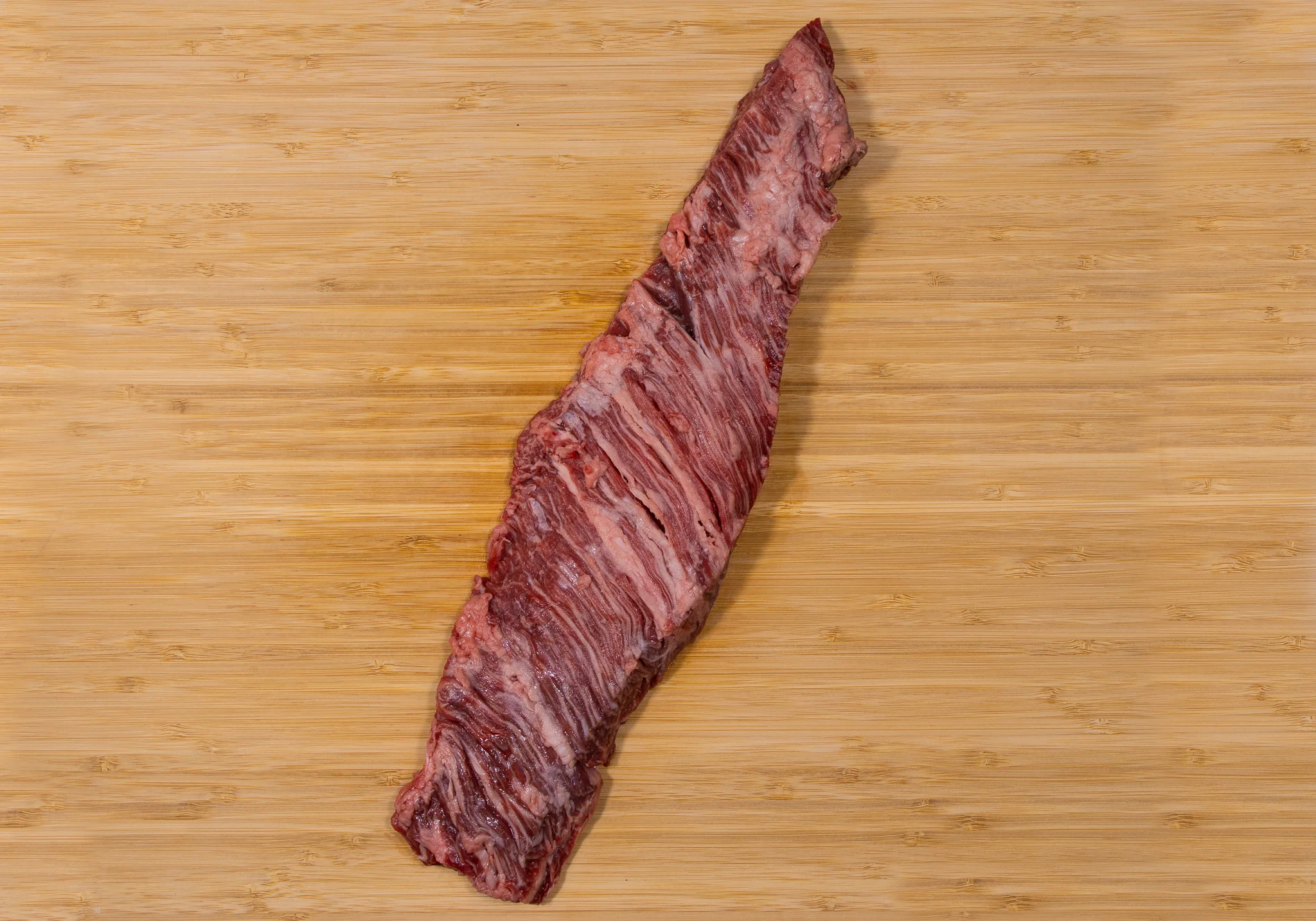 Raw flank steak on a wooden cutting board