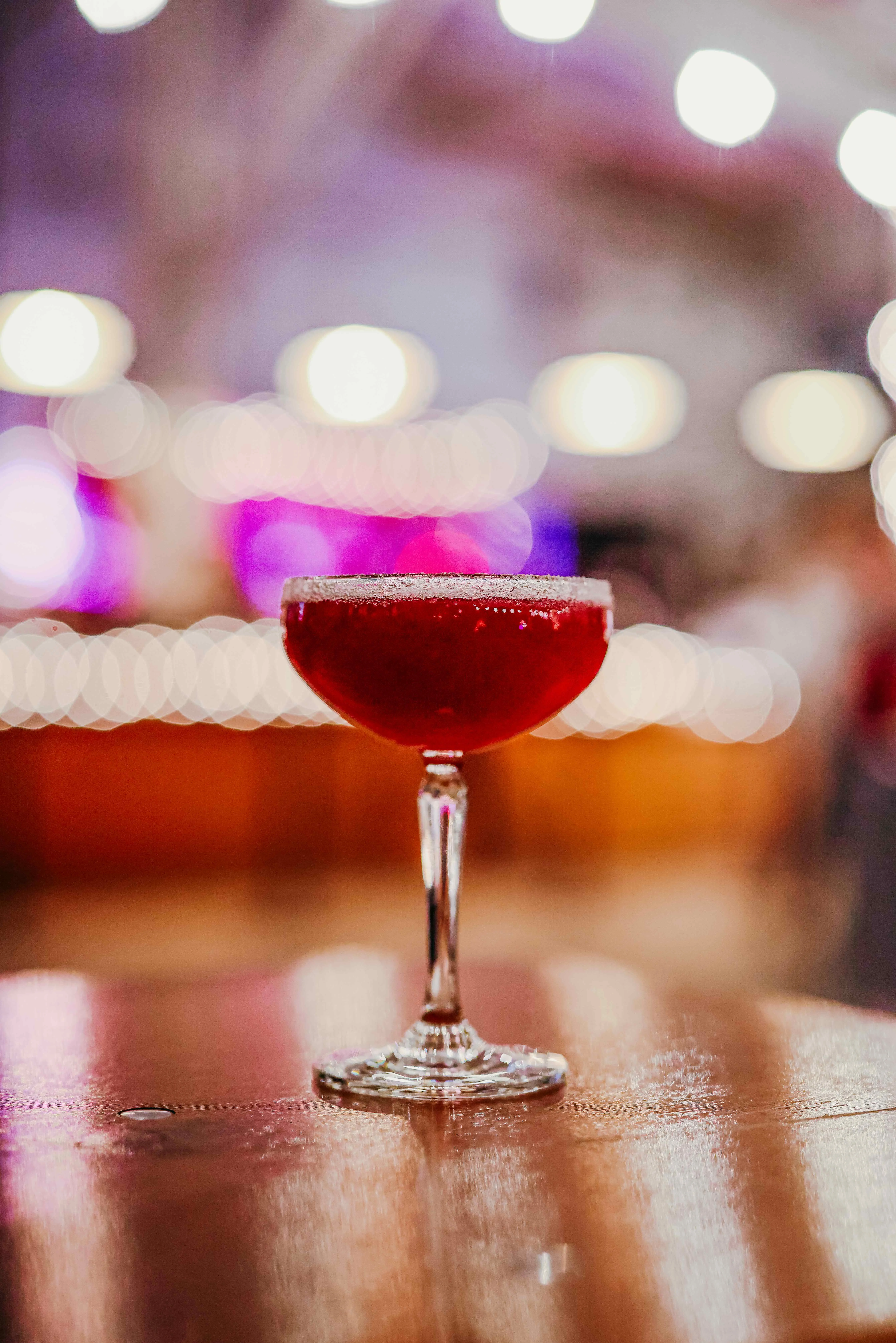 Elegant cocktail served in a coupe glass at a vibrant bar