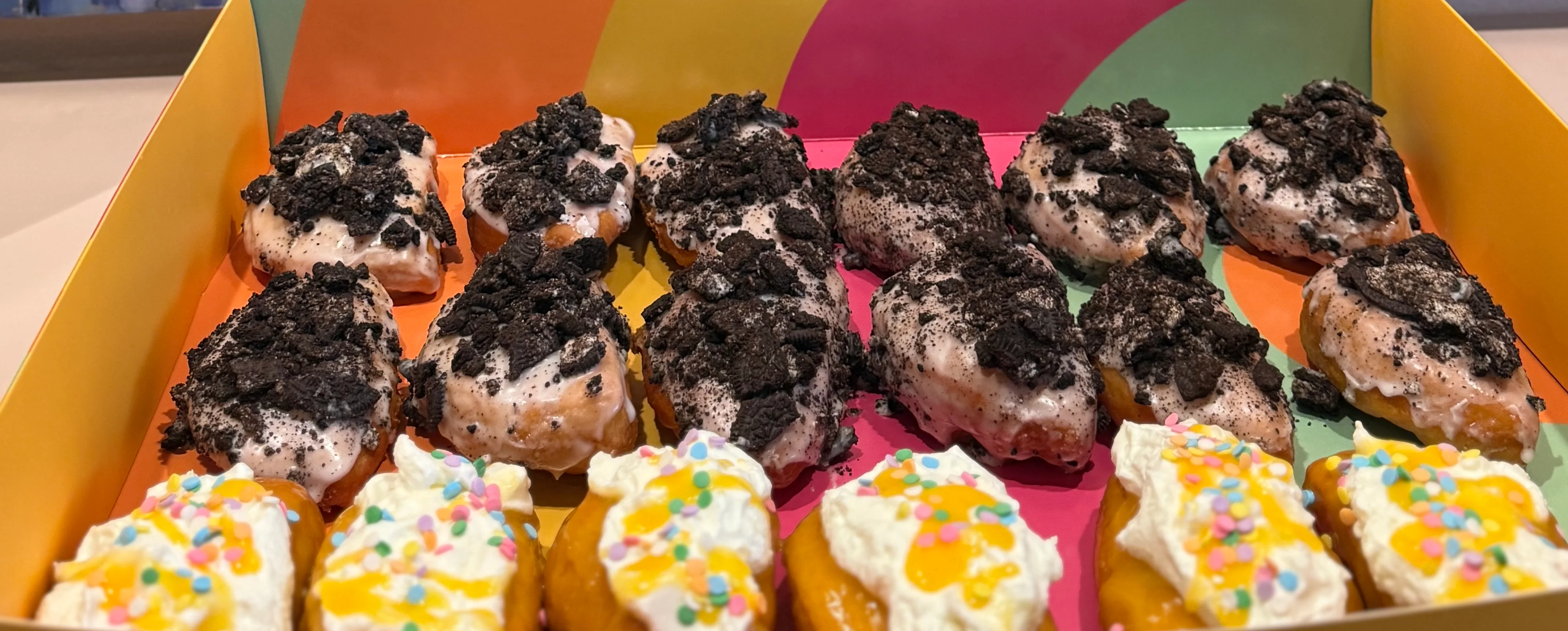 Colorful box of mini donuts with toppings and playful design