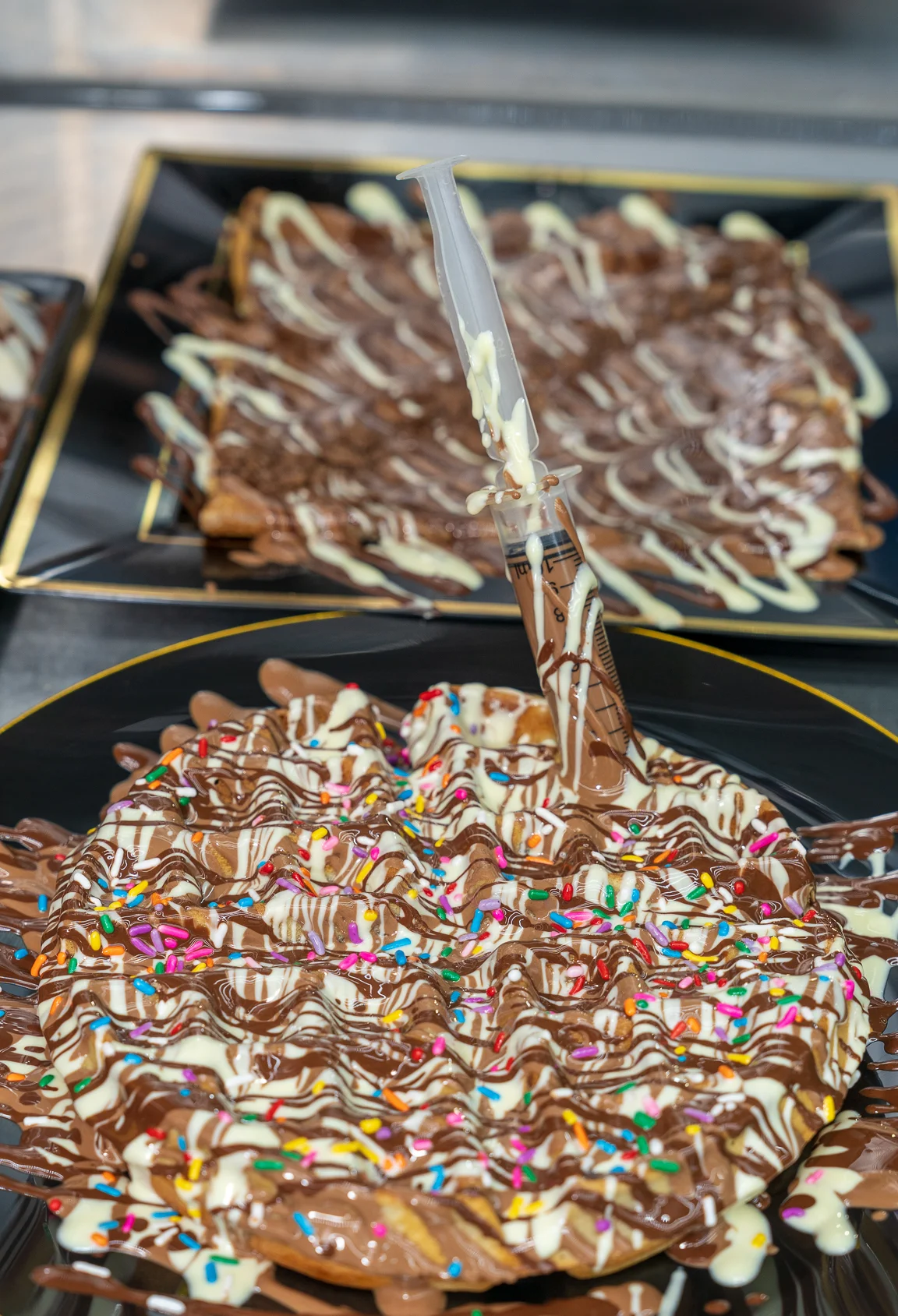 Decadent chocolate waffle with sprinkles and sauce injector