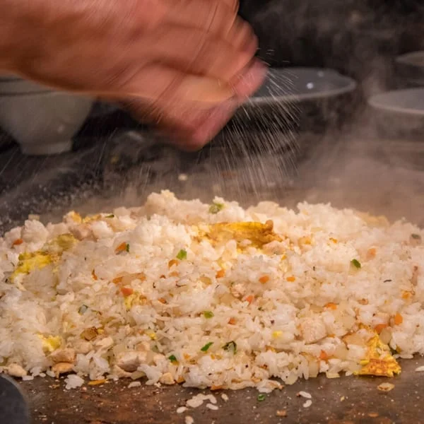 Chef preparing fried rice with vegetables and egg on a hot grill