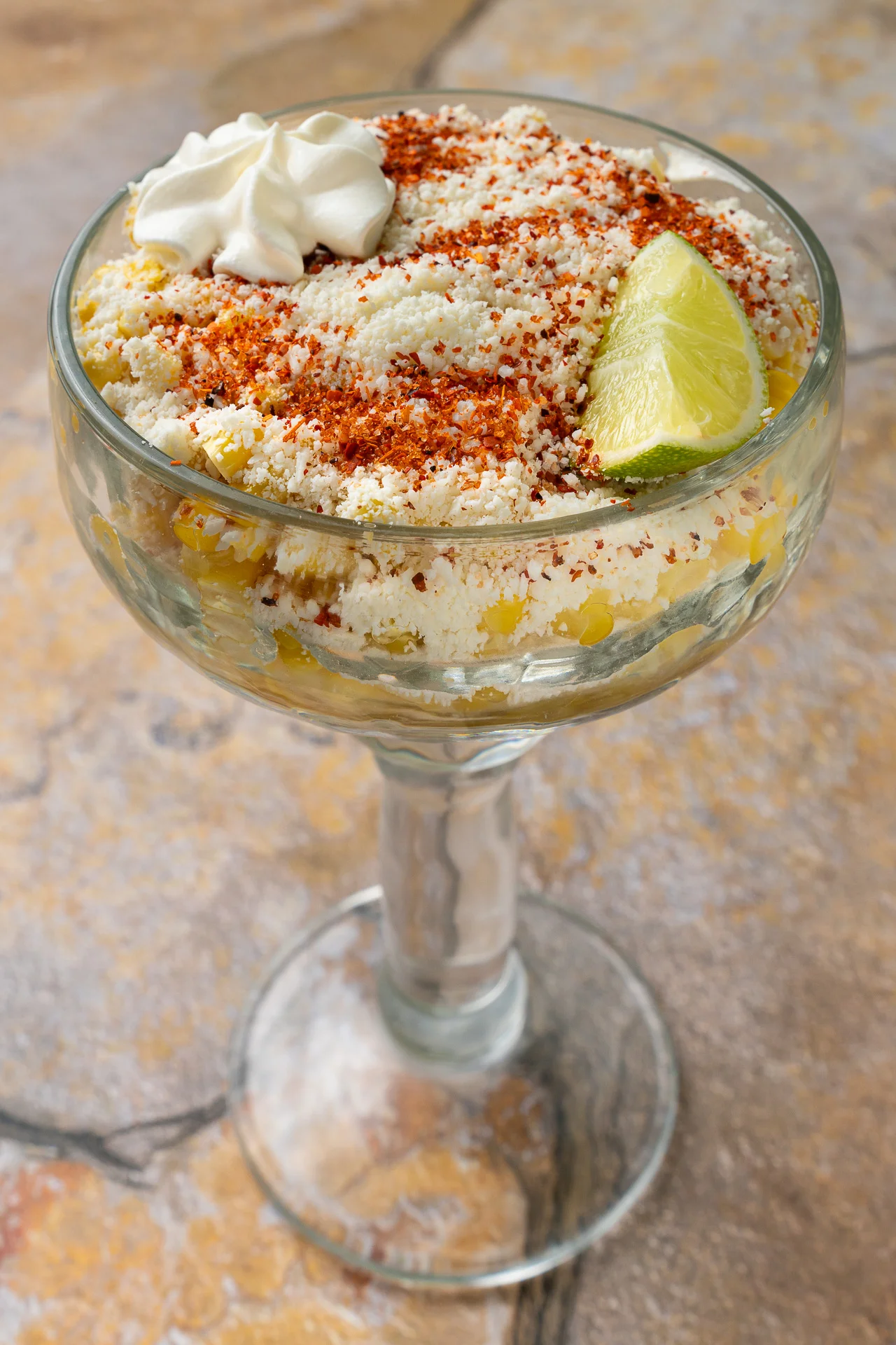 Mexican esquites served in a glass with lime and chili