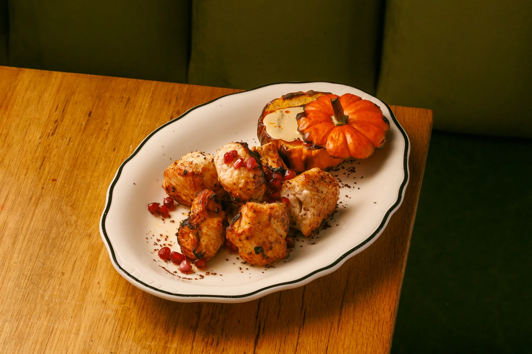 Turkey mtsvadi with walnut satsivi and a small roasted pumpkin on a white platter