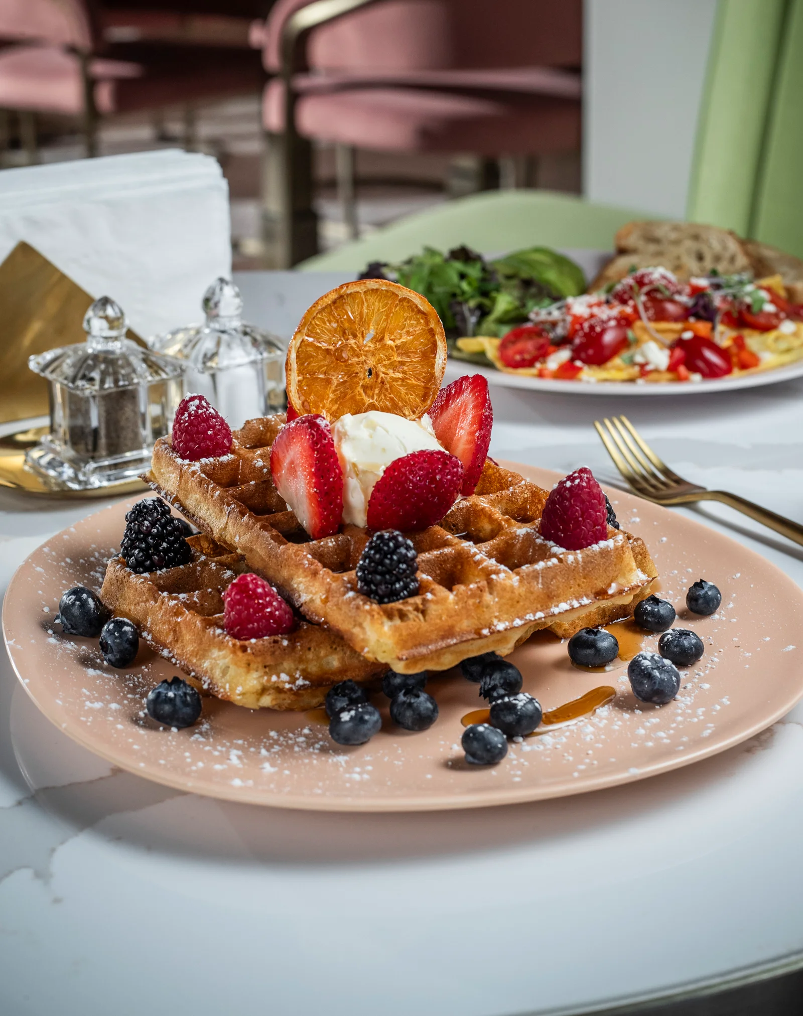 Waffles with a variety of berries and powdered sugar.