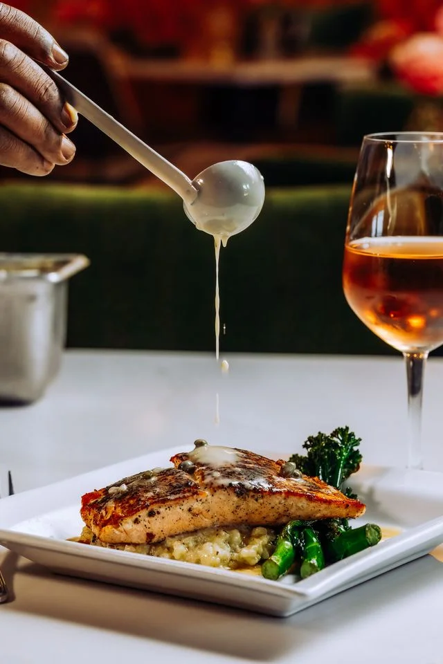 Grilled salmon with creamy sauce and vegetables on a white plate