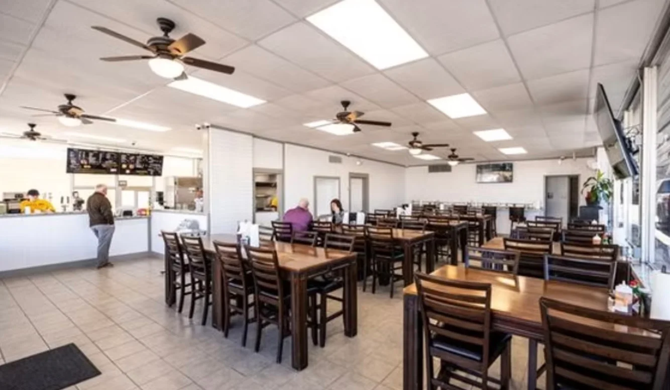 Spacious restaurant interior with wooden tables and ceiling fans