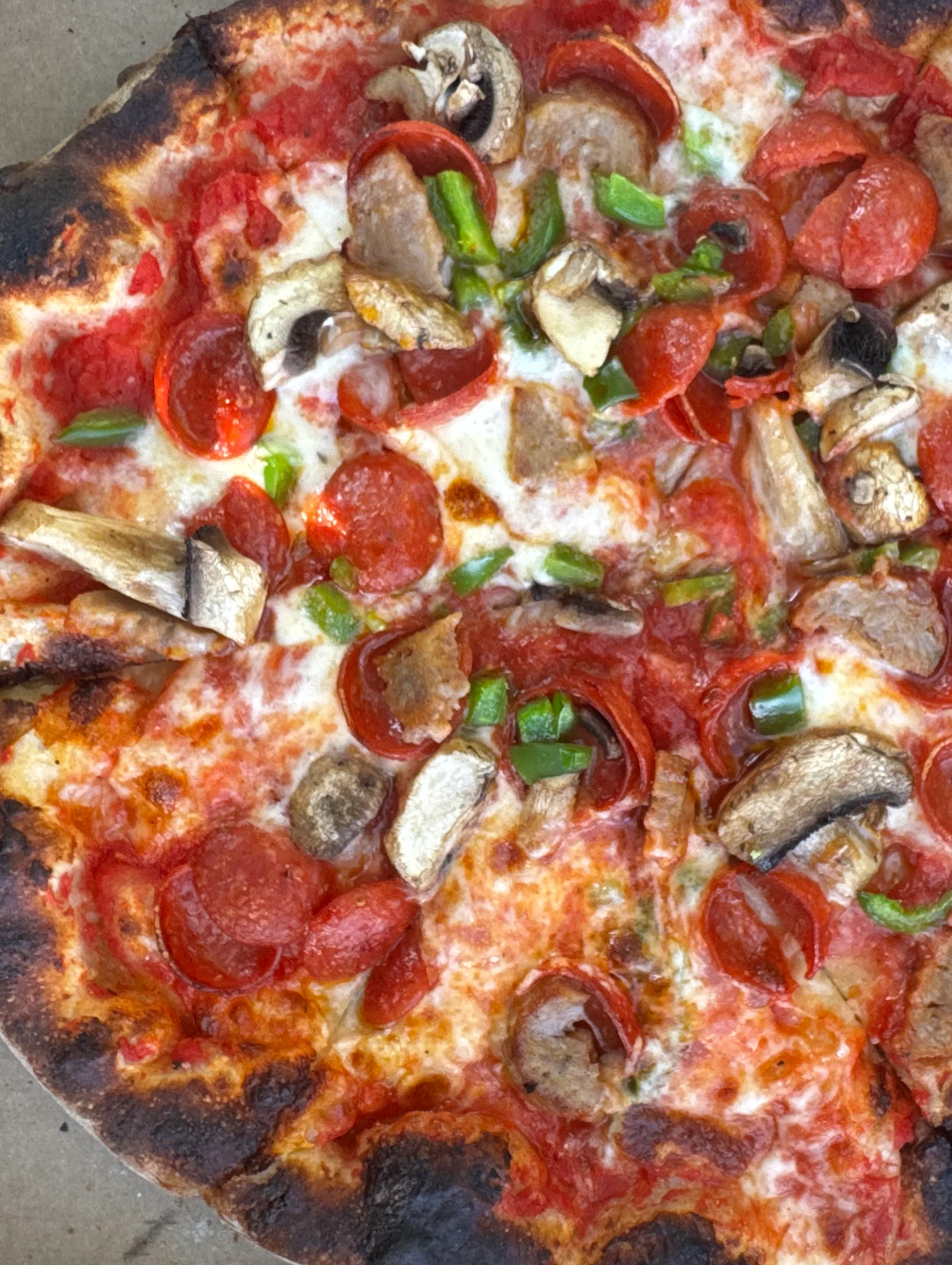 Close-up of Italian pizza with pepperoni, mushrooms, peppers, and melted cheese